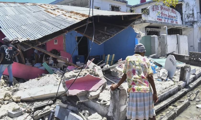 Mulher observa o que sobrou de uma casa que desabou no terremoto deste sábado (14), em Les Cayes, no Haiti. (Foto: Duples Plymouth/AP)