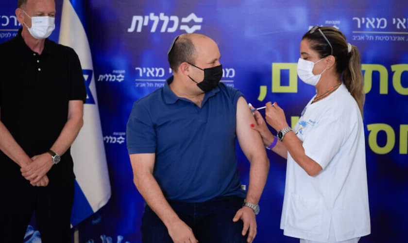 O primeiro-ministro israelense Naftali Bennett recebe a terceira dose da vacina Covid-19, em Kfar Saba. (Foto: Olivier Fitoussi/Flash90).