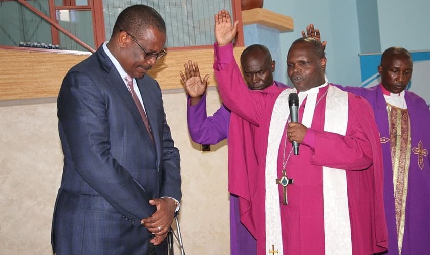 Joseph Ntombura, bispo da Igreja Metodista no Quênia, ora pelo ex-governador de Nairóbi Evans Kidero em 2015. (Foto: Fredrick Nzwili/RNS)