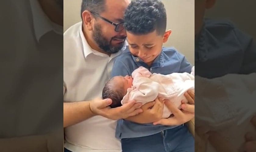Momento em que João Prudêncio Neto e seu filho Davi recebem a pequena Giovanna nos braços. (Foto: Captura de tela/Vídeo Facebook)