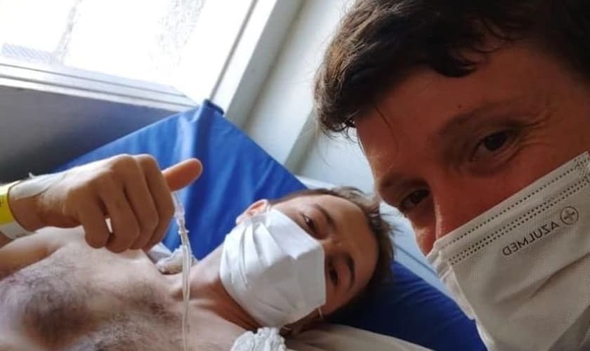 Arlen Isaak dá um sinal de positivo ao receber visita de um amigo no hospital. (Foto: Cynthia Isaak/Facebook)