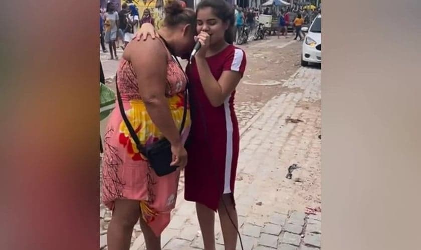 Kemily Maciel abraça mulher que se emociona enquanto ela canta uma música gospel em Fortaleza. (Foto: Arquivo pessoal)