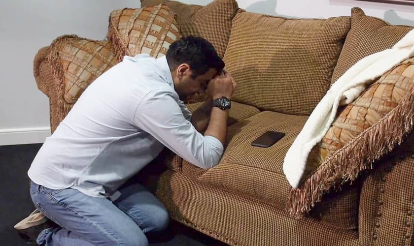 Imagem ilustrativa de homem orando ao lado do telefone. (Foto: Heart4Iran/Facebook)