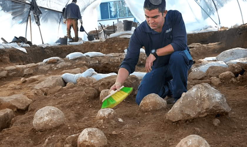Kfir Arbiv, diretor de escavação da Autoridade de Antiguidades de Israel, limpa uma pedra balista no Complexo Russo. (Foto: Yoli Schwartz/Israel Antiquities Authority)
