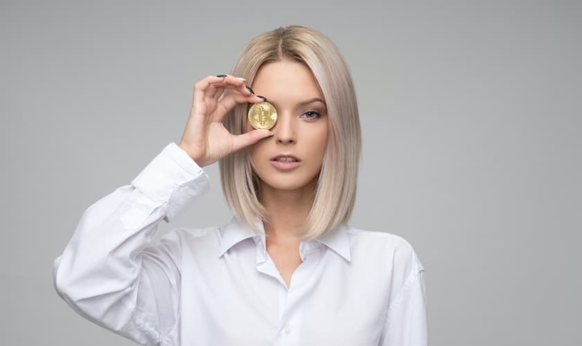 Imagem ilustrativa de mulher segurando Bitcoin. (Foto: Icons8 Team/Unsplash)