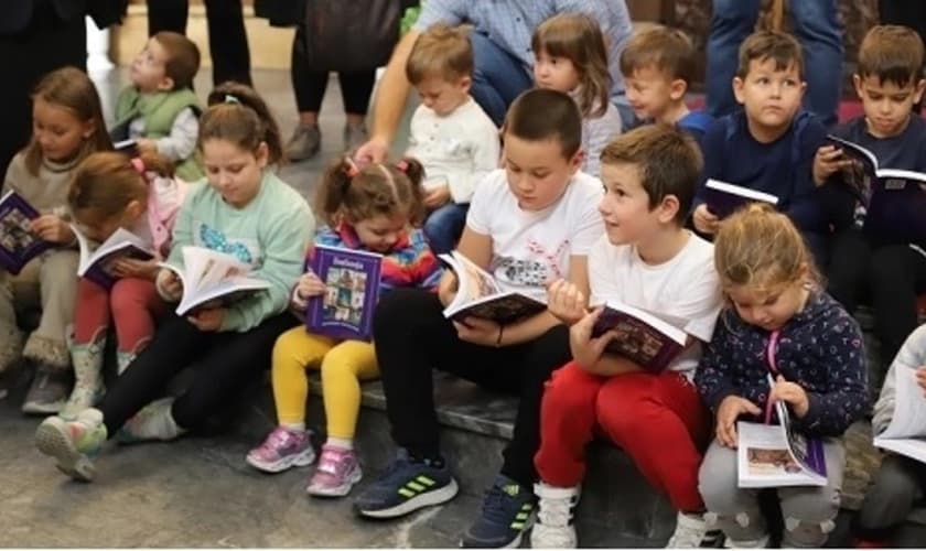 Crianças da Macedônia do Norte leem Bíblias entregues pela EEM em 2022. (Foto: Reprodução/EEM)