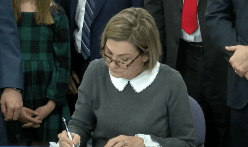 A governadora de Iowa, Kim Reynolds, enquanto assina nova legislação. (Captura de tela/ YouTube/We Are Iowa Local 5 News)