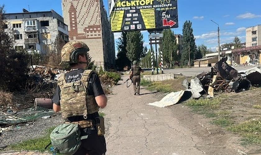 Soldado ucraniano escolta missionários por uma cidade destruída nos arredores de Pokrovsk. (Foto: Free Burma Rangers)