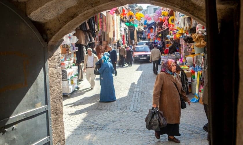 Homens e mulheres caminham por um mercado que vende roupas, alimentos e artigos para o lar em um bairro de Istambul, Turquia. (Foto: IMB)