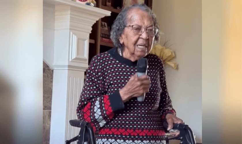 Apoiada em um andador e segurando um microfone, idosa centenária louva a Deus. (Captura de tela/Instagram/sherese.conner)